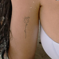 Flower tattoo with a long stem in a minimalist style.